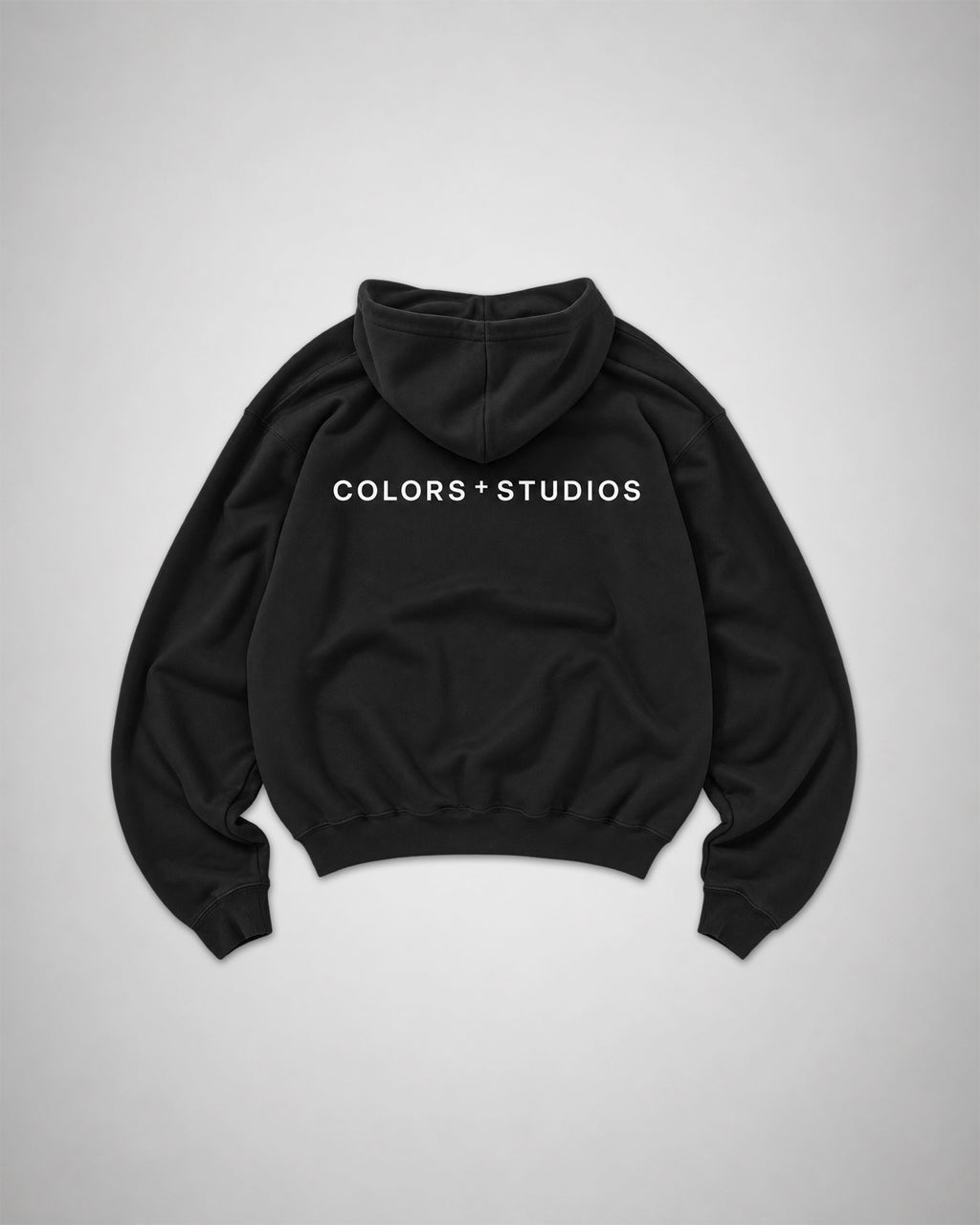 Back view of black COLORS+STUDIOS hoodie with white logo print across the upper back.