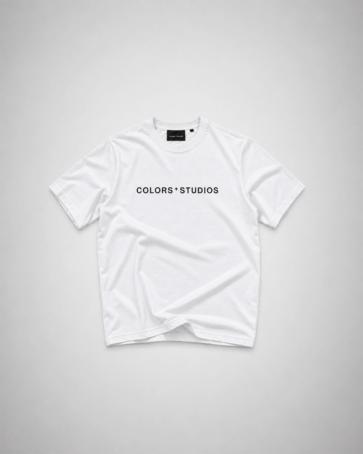 White T-shirt with black COLORS+STUDIOS logo printed across the chest.