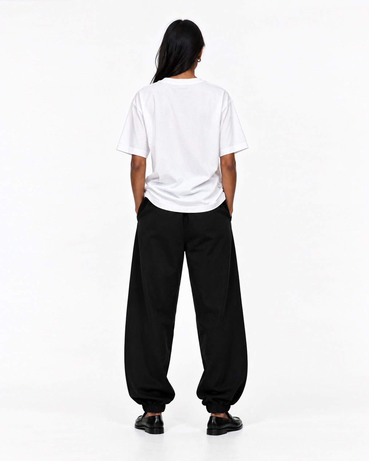 Back view of model wearing a white COLORS+STUDIOS T-shirt styled with loose black trousers.


