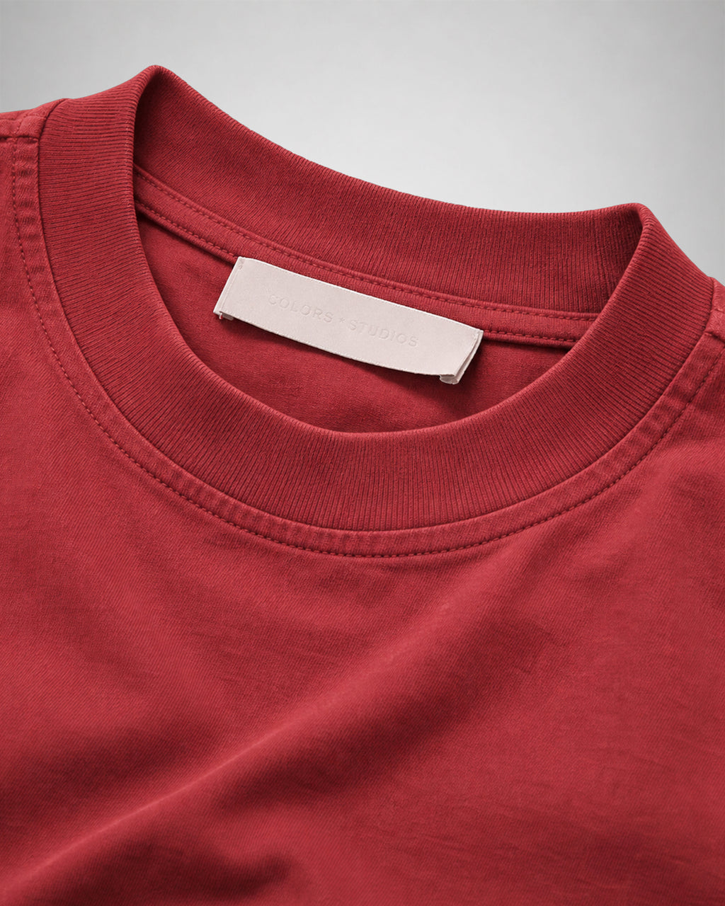 Close-up of the ribbed crew neck and woven neck label on the Sundown red COLORS T-Shirt