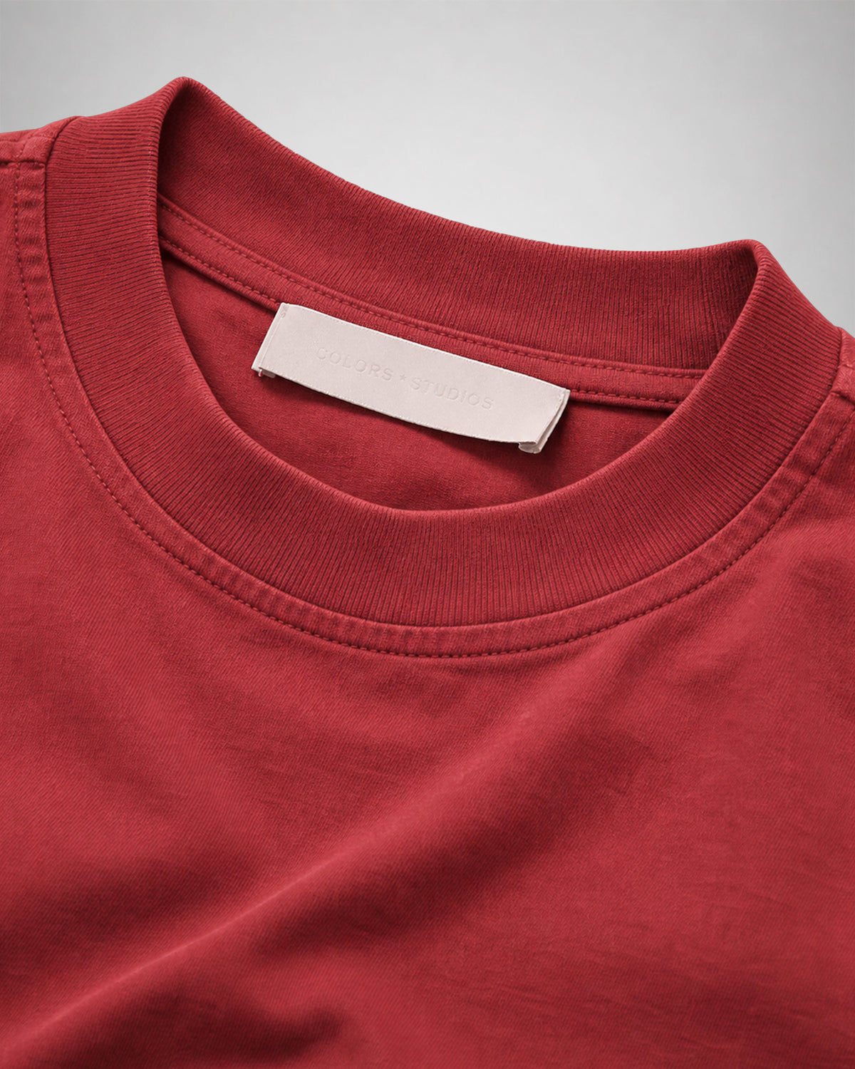 Close-up of the ribbed crew neck and woven neck label on the Sundown red COLORS T-Shirt