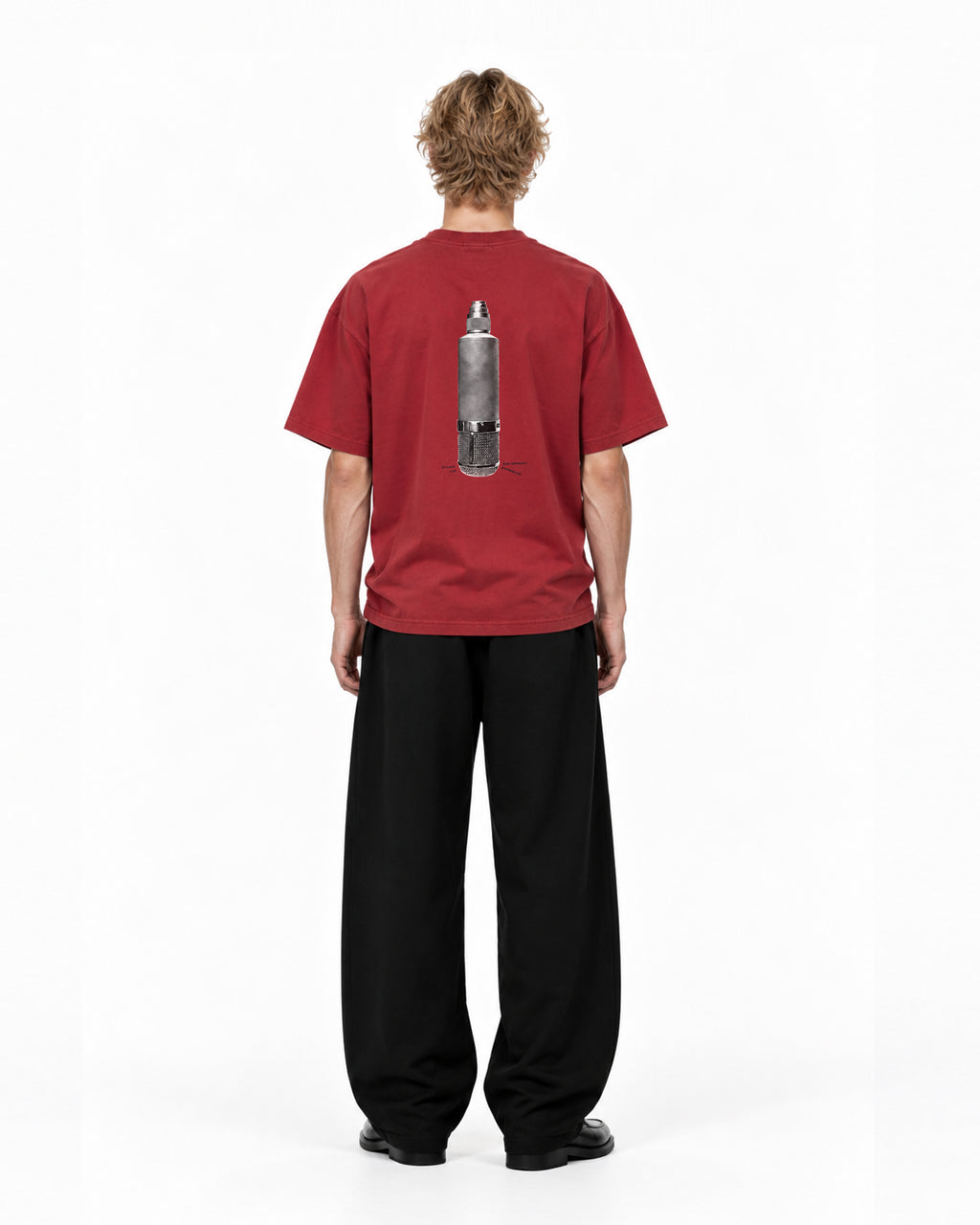 Model wearing the COLORS Mic T-Shirt in Sundown red, back view showing the microphone print, full length
