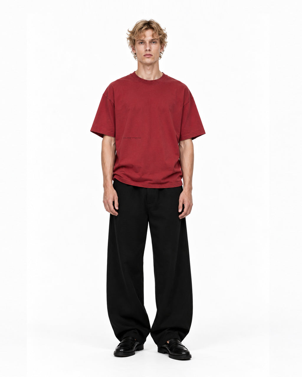 Model wearing the red COLORS Mic T-Shirt in Sundown with black wide-leg trousers, front view, full length