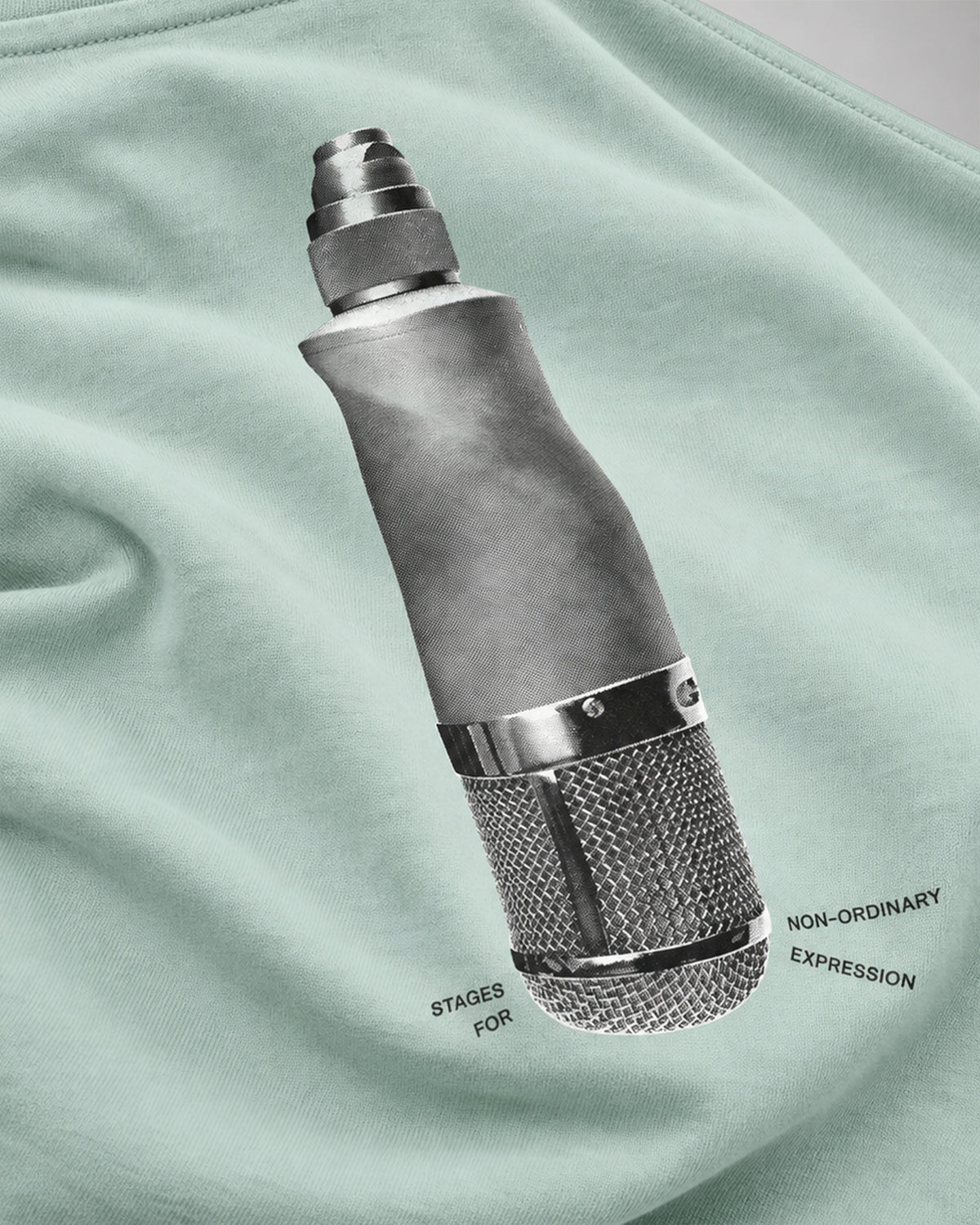 Close-up of the halftone microphone screen print with the line STAGES FOR NON-ORDINARY EXPRESSION on the mint green COLORS Mic T-Shirt