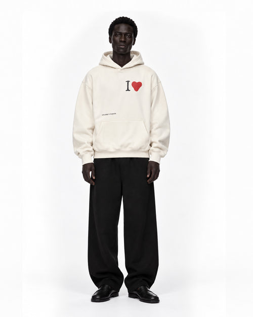 Model wearing the off-white COLORS I Love Hoodie in Pearl Canvas with black wide-leg trousers, front view, full length